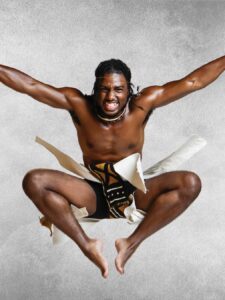 Young Man in African skirt jumping while dancing