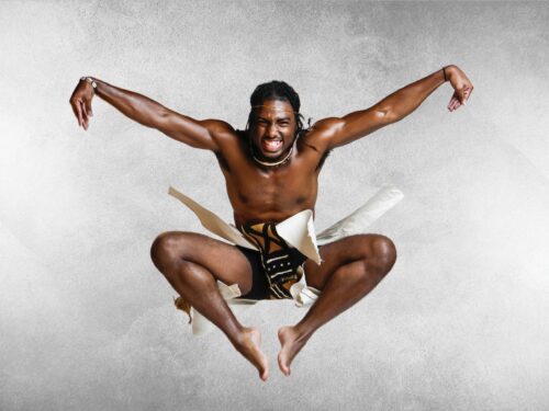Young Man in African skirt jumping while dancing