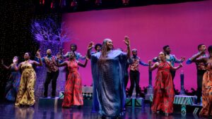 Cast of Joyful Joyful on stage in brightly colored African Looking costumes