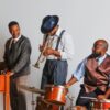 Three men playing musical instruments - piano, trumpet and drums in 1950s attire