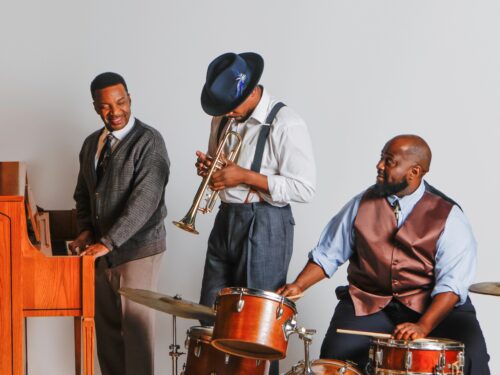 Three men playing musical instruments - piano, trumpet and drums in 1950s attire