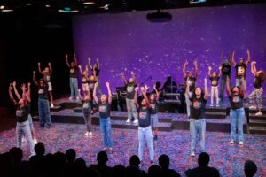 Kids on stage with their arms in the air