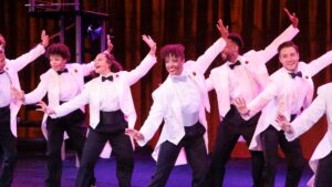 Dancers with white coats posing with arms up.