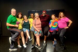 Group of people in brightly colored clothing posing with legs up and bent.