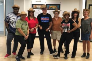 Group of people dressed up in cowboy hats posing for the camera.