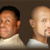 Two black men sitting back to back looking at the camera