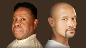 Two black men sitting back to back looking at the camera